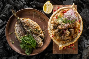 Balık ve otlar ve et ve kömür pişirme baharatlar ile ev yapımı ekmek ile plaka