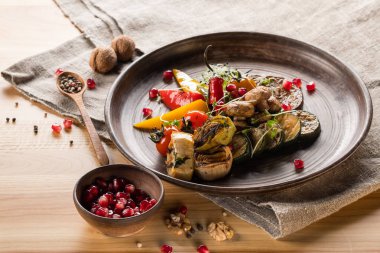 Nar ile kase tahıllar, ahşap masa üzerinde baharatlar ile plaka, ceviz ve tahta kaşık ızgara sebze, yakın çekim