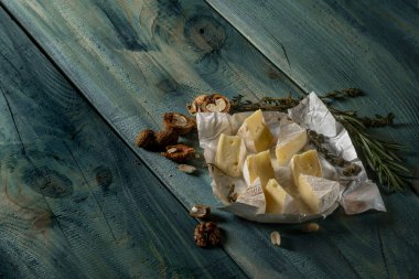 Brie peyniri dilimleri, otlar ve fındık mavi ahşap arka plan, kopya alanı ile Üstten Görünüm