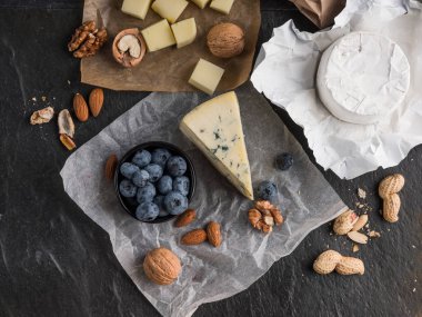 zeytinyağı, yaban mersini ve fındık, üstten görünüm ile ahşap tahta üzerinde çeşitli peynir dilimleri