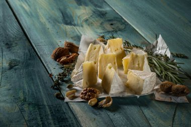 rustik düz lay camamber peynir dilimleri, otlar ve mavi ahşap arka plan, kopya alanı ile üstten görünüm fındık ile