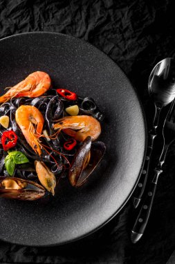 istiridye, karides ve biber kaşık ve çatal, üstten görünüm ile siyah plaka üzerinde