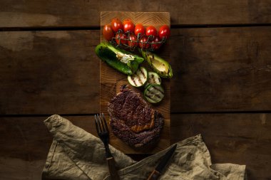 ahşap masa peçete, çatal ve bıçak üzerinde ızgara sebze ve et Üstten Görünüm