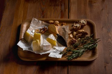 brie peyniri dilimleri, otlar, fındık ve bıçak ile ahşap tepsi, yakın çekim