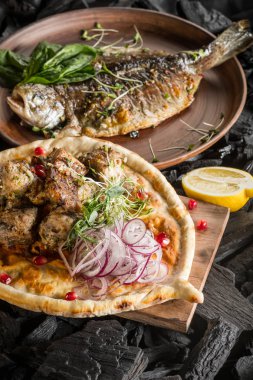 Balık ve otlar ve et ve kömür pişirme baharatlar ile ev yapımı ekmek ile plaka