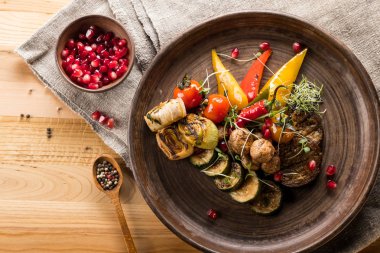 nar taneleri ile kase, ahşap masa, üstten görünüm üzerinde baharatlar ile plaka ve tahta kaşık ızgara sebze