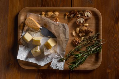 brie peyniri dilimleri, otlar, fındık ve bıçak ile ahşap tepsi, yakın çekim