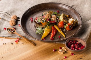 Nar ile kase tahıllar, ahşap masa üzerinde baharatlar ile plaka, ceviz ve tahta kaşık ızgara sebze, yakın çekim