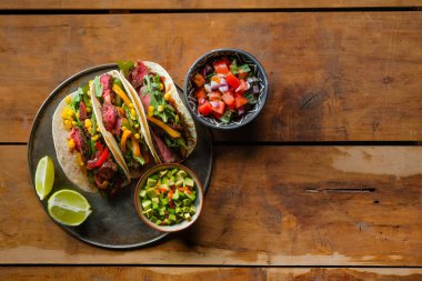 Limon dilimleri ve ahşap arka plan üzerinde kaseler, kopya alanı ile üst görünüm kesilmiş sebzeler lezzetli tacos