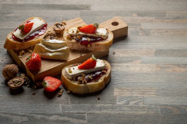 çilek, fındık ve kopya alanı ile ahşap masa üzerinde peynir ile lezzetli sandviçler