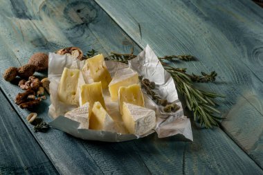 rustik düz lay camamber peynir dilimleri, otlar ve mavi ahşap arka plan, kopya alanı ile üstten görünüm fındık ile