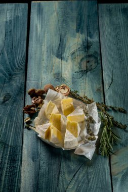 rustik düz lay camamber peynir dilimleri, otlar ve mavi ahşap arka plan, kopya alanı ile üstten görünüm fındık ile