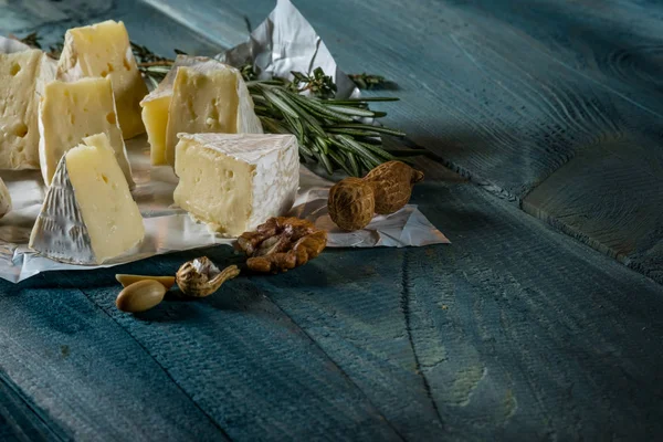 rustik düz lay camamber peynir dilimleri, otlar ve mavi ahşap arka plan, kopya alanı ile üstten görünüm fındık ile