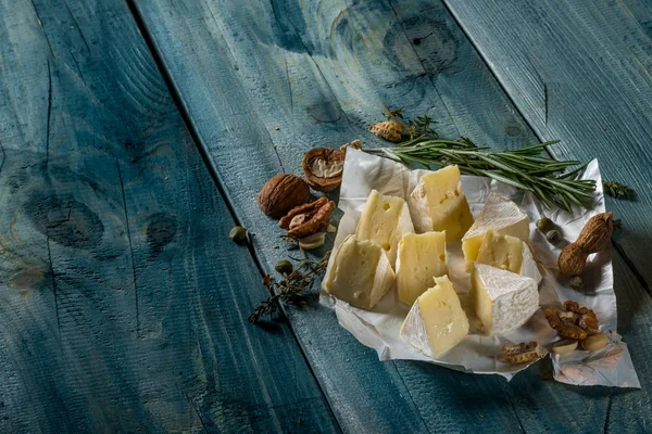 Brie peyniri dilimleri, otlar ve fındık mavi ahşap arka plan, kopya alanı ile Üstten Görünüm