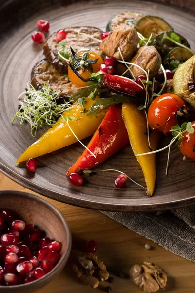 plaka üzerinde ızgara sebze ve nar taneleri ile kase, yakın çekim