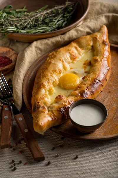 ev yapımı khachapuri, krema, çatal ve bıçak rustik bez, üstten görünüm üzerinde bir kase ile Tablo ayarı 