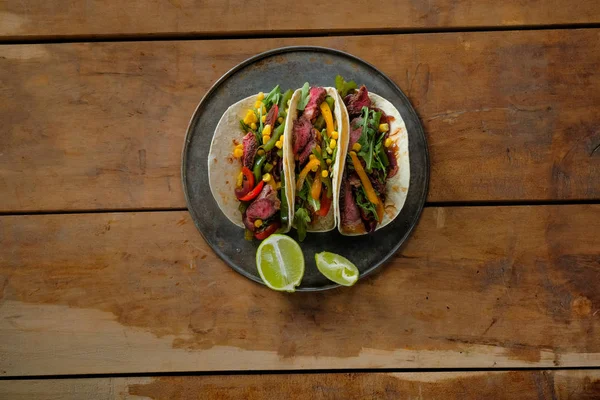 Deliciosos Tacos Com Fatias Limão Placa Preta Fundo Madeira Vista — Fotografia de Stock