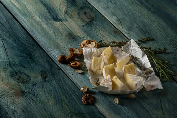 Rebanadas Queso Brie Hierbas Frutos Secos Sobre Fondo Madera Azul — Foto de Stock