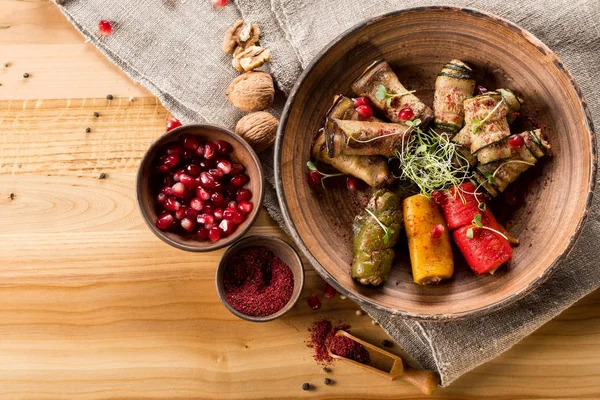 top view of grilled and stuffed vegetables on plate and pomegranate grains in bowl on wooden table