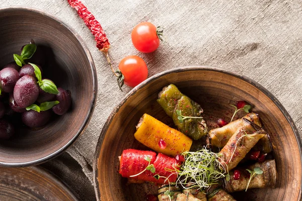 grilled and stuffed vegetables, plums and pomegranate grains on wooden table, close up