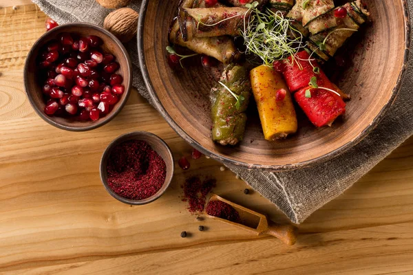 ボウル木製テーブルの上にプレートとザクロの粒焼きとぬいぐるみ野菜のトップ ビュー — ストック写真
