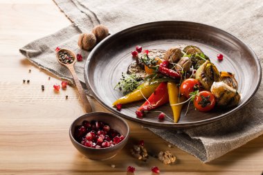 Nar ile kase tahıllar, ahşap masa üzerinde baharatlar ile plaka, ceviz ve tahta kaşık ızgara sebze, yakın çekim