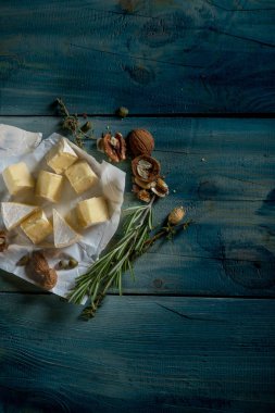 rustik düz lay camamber peynir dilimleri, otlar ve mavi ahşap arka plan, kopya alanı ile üstten görünüm fındık ile