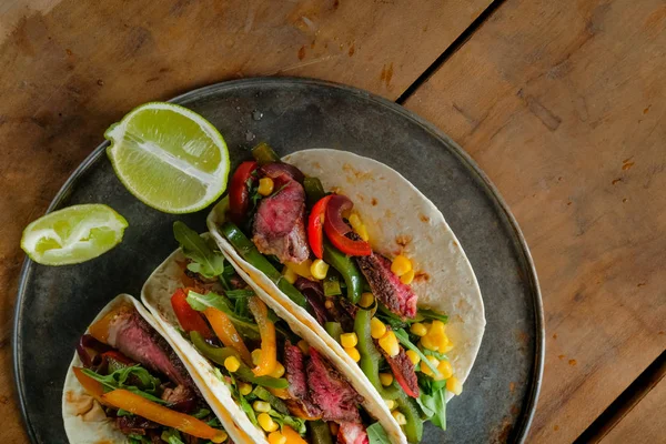 Deliziosi Tacos Con Fette Lime Piastra Nera Sfondo Legno Vista — Foto Stock