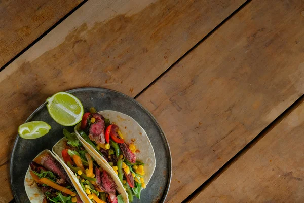 Deliciosos Tacos Com Fatias Limão Placa Preta Fundo Madeira Vista — Fotografia de Stock