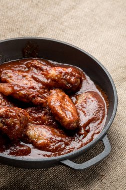 kopya alanı ile rustik kumaş üzerine demir tavada kırmızı sos ile kavrulmuş tavuk Üstten Görünüm
