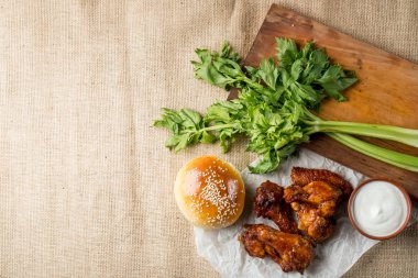 Buffalo tavuk kanatları ve ahşap tahta kase, kopya alanı ile üstten görünüm peynir sos ile servis üzerinde susam ile topuz