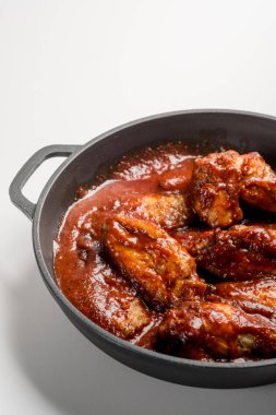 demir tavada kırmızı soslu kızarmış tavuk bakış beyaz masada kapatın