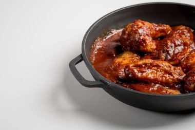 Demir kırmızı soslu kızarmış tavuk tava kopya alanı ile beyaz tabloda