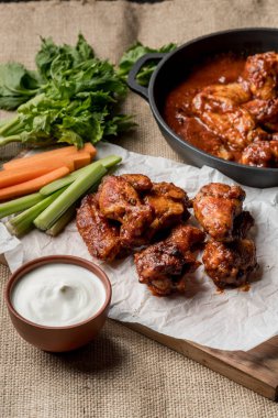 Sebze çubukları ve peynir soslu beyaz masada Buffalo tavuk