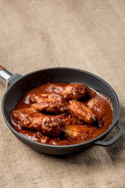 kopya alanı ile rustik kumaş üzerine demir tavada kırmızı sos ile kavrulmuş tavuk Üstten Görünüm