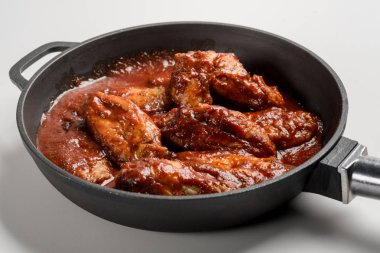 demir tavada kırmızı soslu kızarmış tavuk bakış beyaz masada kapatın