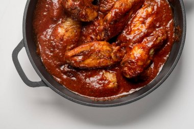 Demir kırmızı soslu kızarmış tavuk tava beyaz masaya Üstten Görünüm