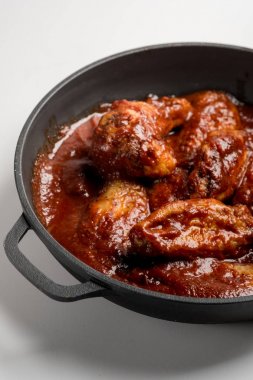 demir tavada kırmızı soslu kızarmış tavuk bakış beyaz masada kapatın