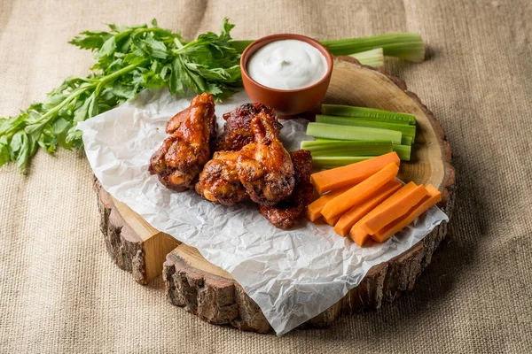 Buffalo chicken wings on rustic background with vegetables slices