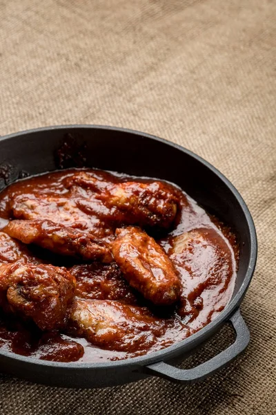 kopya alanı ile rustik kumaş üzerine demir tavada kırmızı sos ile kavrulmuş tavuk Üstten Görünüm