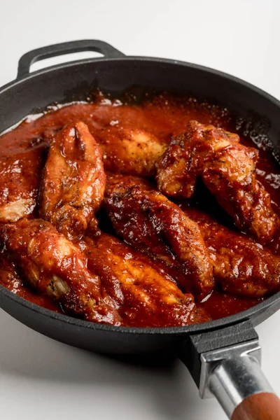 demir tavada kırmızı soslu kızarmış tavuk bakış beyaz masada kapatın