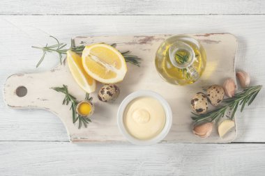 bıldırcın yumurtası, zeytinyağı, limon, sarımsak ve biberiye Beyaz ahşap kesme tahtası, üstten görünüm üzerinde sos