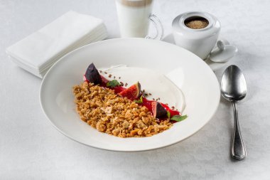 İncir ve yoğurt kahve fincanı, üstten görünüm ile beyaz tabloda granola