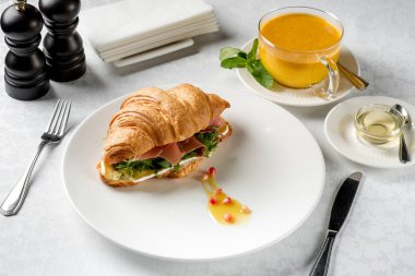 Bitkisel çay ve bal ile servis beyaz masada taze kruvasan sandviç