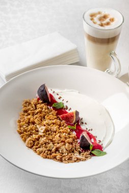 Granola incir ve yoğurt kahve fincanı, beyaz tablo ile yakın çekim