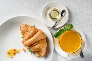 Bitkisel çay, üstten görünüm taze kruvasan sandviç beyaz masada servis