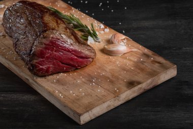 Sarımsak ve biberiye siyah arka plan üzerine bir kesme tahtası üzerinde ham taze sığır filetosu