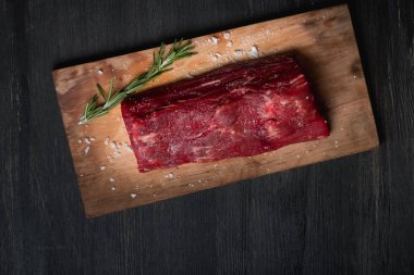 Siyah arka plan üzerine bir kesme tahtası üzerinde ham sığır filetosu. Yukarıdan düz görünüm, top