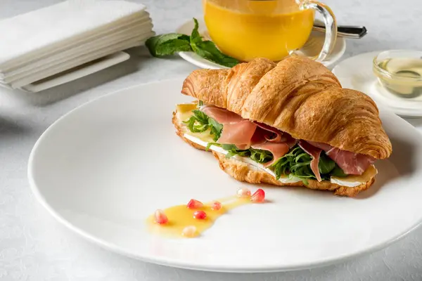 Fresh croissant sandwich served with tea herbal
