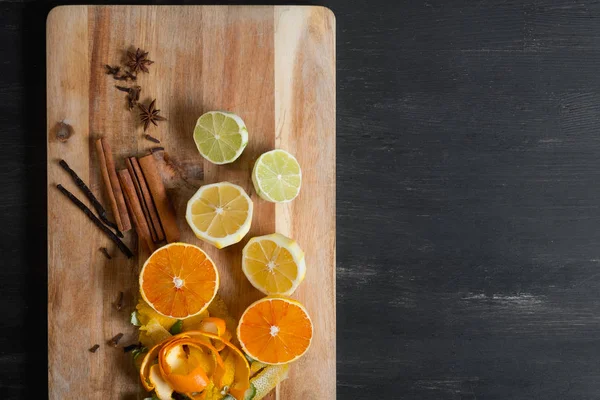 peeled citrus fruits with cinnamon sticks and anise stars on wooden background, top view with copy space